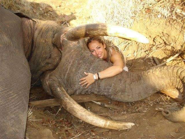 Trophy-hunter posing with her dead victim. These types of humans contribute nothing to society. They exist only to extinguish innocent life and to mock those who care about such life. 

These types of humans are unproductive, harmful, and useless, and thus, expendable.