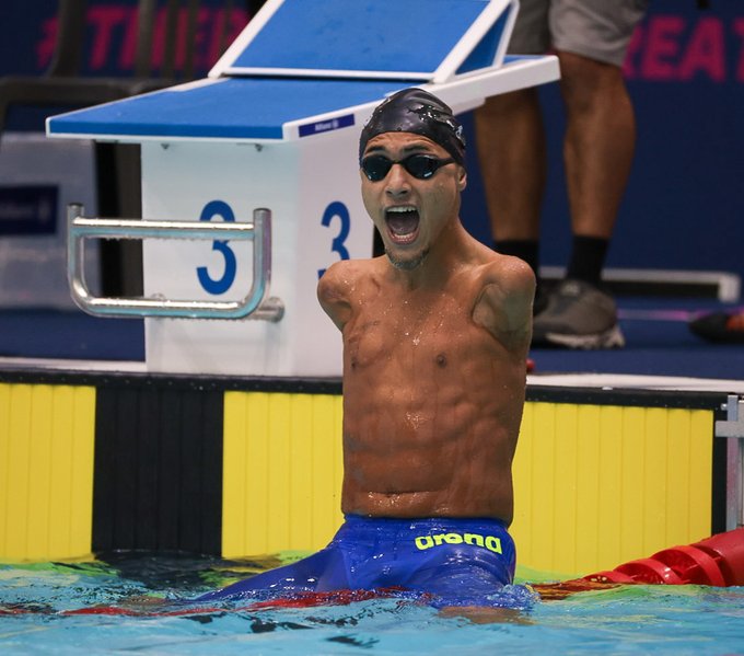 Foto do atleta Samuel Oliveira gritando sentado na raia da piscina em comemorao ao ttulo de campeo mundial.