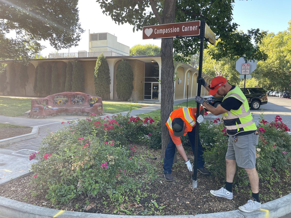 Two workers put up a sign that says “Compassion Corner”