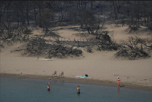 sundaylongread's tweet photo. Fatal heatwaves and dry conditions have fueled a harsh, deadly fire season in Greece. AP photographer @PGiannakouris documented the jarring reality of beachgoers still trying to enjoy themselves, with a charred forest as their abstract backdrop. #SundayStill https://t.co/8ZnFj5ltj5