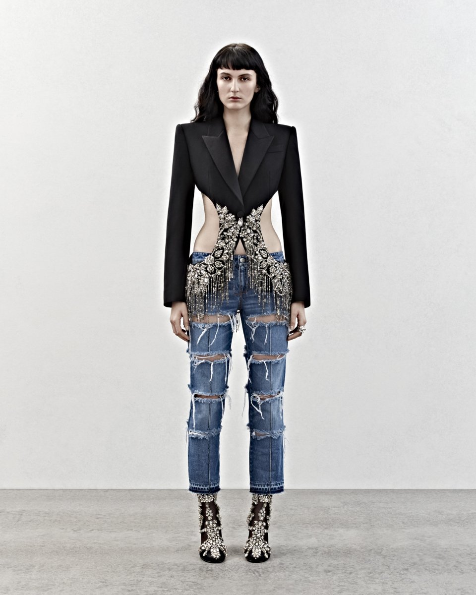 McQueen's tweet photo. Close up crystal embroidery detailing adorns the #McQueenPreAW23 cutaway tailored jacket. Worn with slashed blue denim bumster jeans and crystal embroidered Pin heel boots. 

Discover the collection: https://t.co/t2E1ly6QGD https://t.co/UxTUlp856P