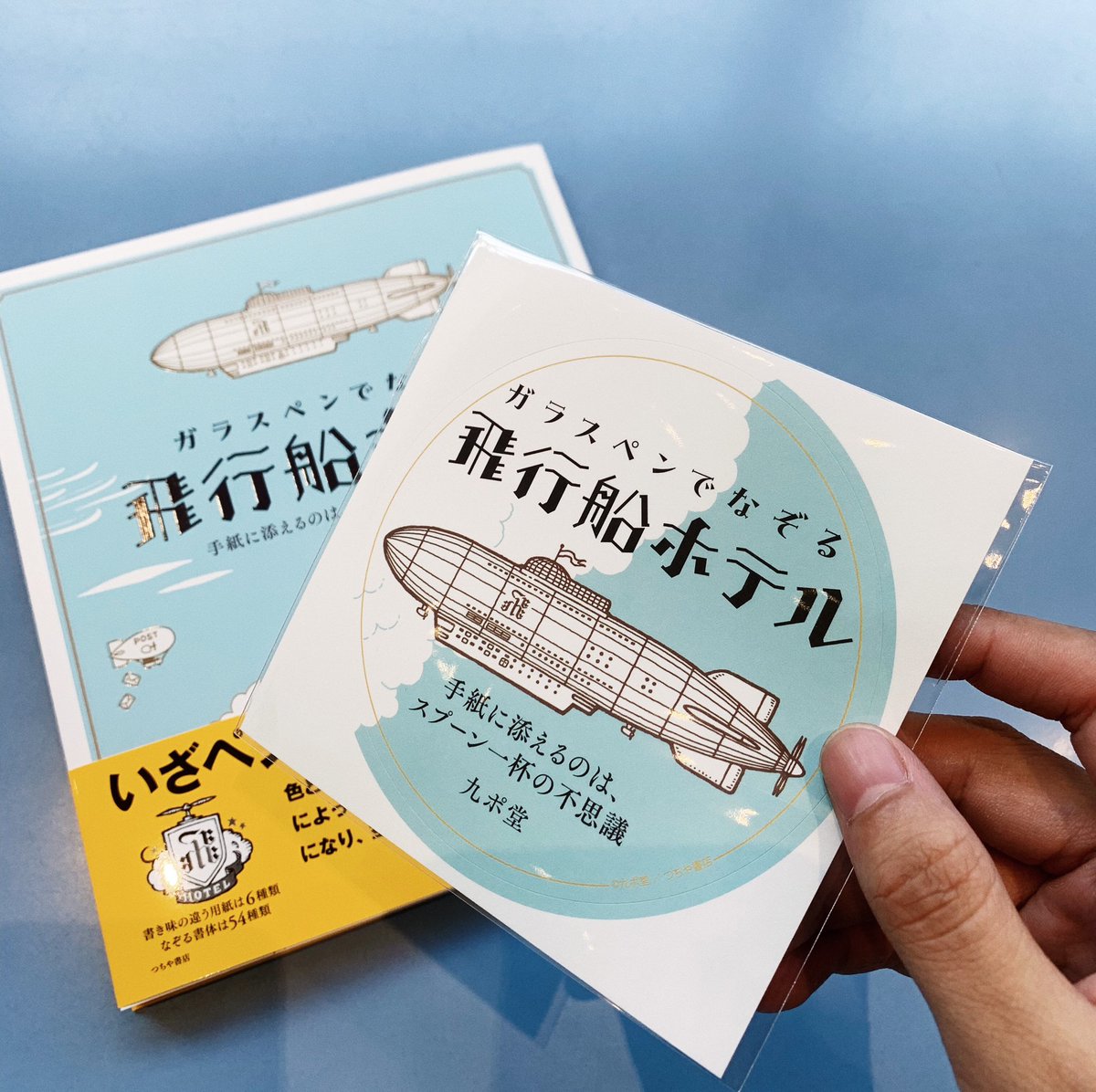 【神田店】『ガラスペンでなぞる 飛行船ホテル』入荷！！
九ポ堂さんファン待望の『ツキアカリ商店街』に続き第二弾！空や海の5つの旅がテーマ。不思議な物語が広がるわくわくする一冊になっています。特別ステッカーもご用意しています、数に限りがあるのでお早めにお買い求めください！
#九ポ堂