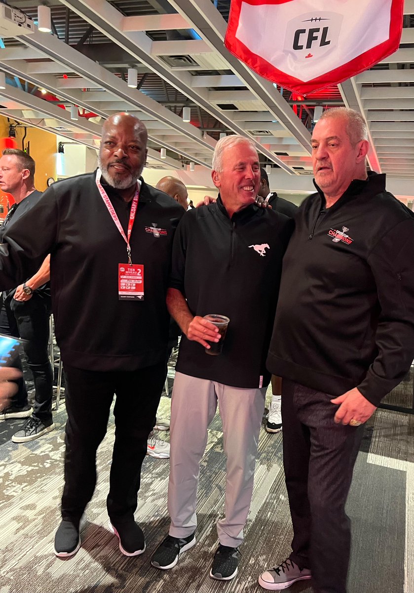 Jackie Kellogg (left) signs footballs; and (right) Stampeders’ current president and past coach John Hufnagel (middle) chats with Freddie Childress and Bruce Covernton at reunion of 1998 Grey Cup champions on Friday. Nearly three dozen players and staff from the team attended.