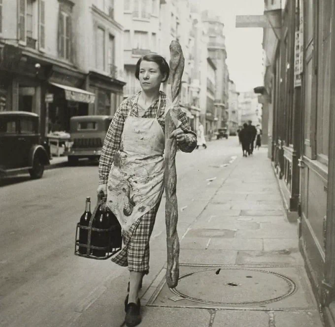 Fransız bir kadın, büyük bir baget ve altı şişe şarapla Paris, Fransa sokaklarında yürüyor, 1945.