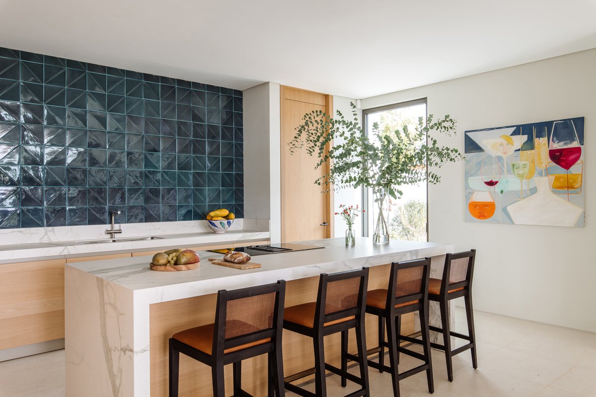 A fresh and vibrant kitchen with bespoke wooden bar stools in an espresso finish and natural jute rope, a sharp teal tile backsplash, and crisp white walls. As ever, the space is brought to life by the artwork.
