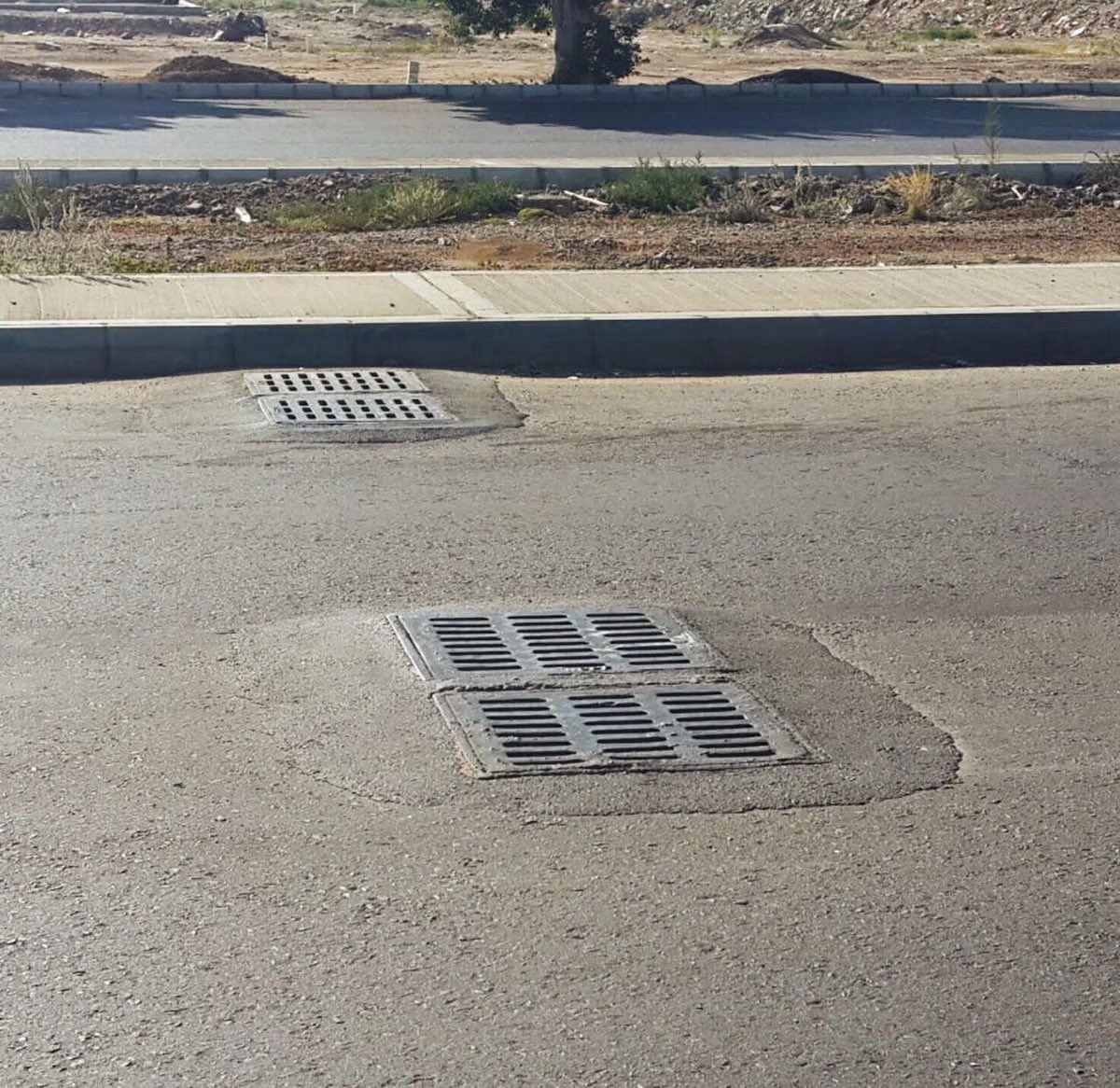 هل يجب أن تكون فتحة تصريف مياه الأمطار أعلى من سطح الطريق؟ 
أم أن الأسفلت يهبط مع مرور الوقت؟
ام سوء تنفيذ؟