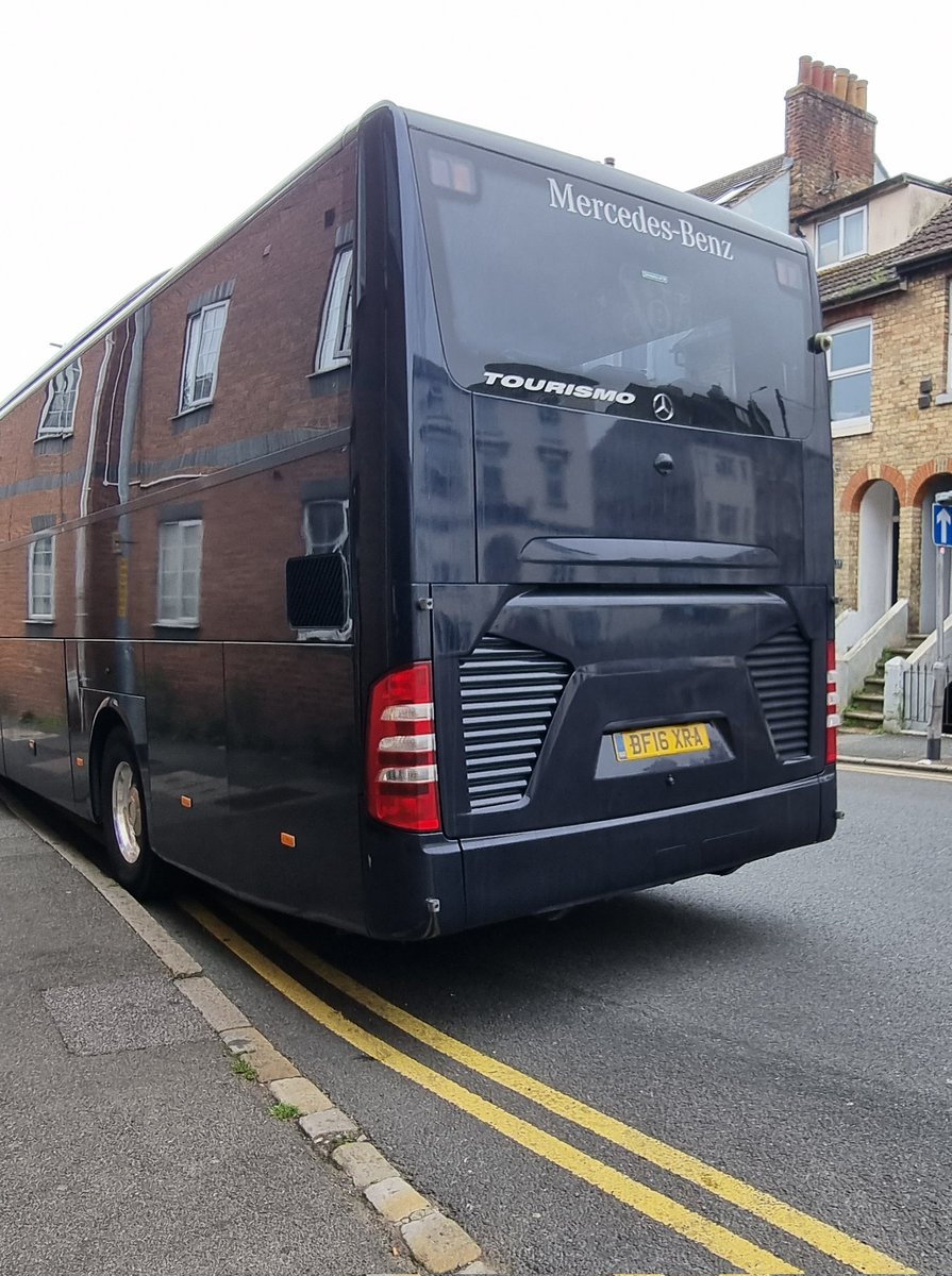 Heres a photo of a Home Office contracted bus parked on double yellows on a one way street and kn a corner.