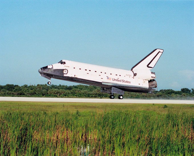 Side angle shot of Space Shuttle landing on an airfield.