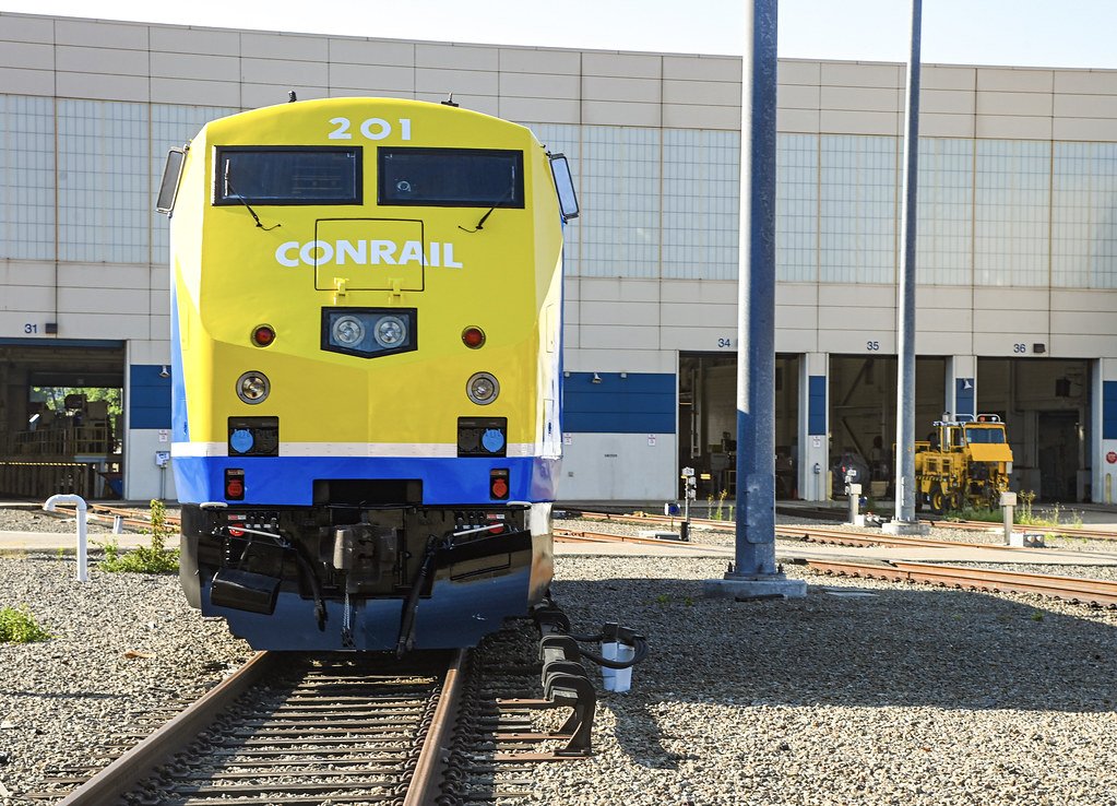 A blue and yellow Metro-North train, adorned with the Conrail and 40th anniversary logos.