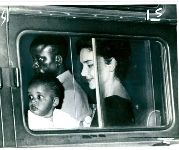 Thriving_luos's tweet photo. Memba Kenyatta, a Kenyan man claiming to be Kenyatta's son, is shown inside an Italian police vehicle in Rome in 1960, with his wife, Julia Gonzalez Memba, and infant, after being imprisoned for raising problems. Memba, claiming to be Kenyatta's son, had wreaked havoc on the route veneto by abusing and spitting on passers-by while demanding the release of his "father" Kenyatta.

When his wife attempted to control him, he assaulted her as well. As a result, he was arrested and taken to a mental institution for treatment. Julia Gonzalez de Memba, a journalist from Italy, married Memba in 1956 after he convinced her that he was Kenyatta's son. Gonzalez was happy that her father-in-law was spearheading the battle for independence in Kenya from that point on.
She had no idea she was living with a conman.  Bernard Memba "Kenyatta" often boasted of being Kenyatta's son across Europe, and at one time appeared on an Italian TV station advocating for the release of "his father" from prison. 
It wasn't until early 1962, on a journey to Tanzania, that Julia Gonzalez realized her husband, Memba, was a masquerader and not Kenyatta's son, as he had always claimed.
Memba escaped from Europe to Africa as soon as he realized his falsehoods had been exposed, abandoning his wife and kids. Gonzalez, after being abandoned with her child, insisted that Bernard Memba was still her husband. Divorce, she said, was never in her lexicon, and her husband's acts were not cause enough to end her marriage. 
 On May 30, 1962, she wrote to Jomo Kenyatta and proposed writing his biography in Spanish. The only payment she asked for her labor was for Kenyatta to accept her kid as his grandson, despite the fact that they were not related. "I am requesting  for  little affection for the poor child with dark skin whose father has abandoned him and who still thinks of you as his grandfather," Gonzalez  wrote.
"For  more than five years now I have been living completely convinced of the fact that you were my father-in-law and for this reason my son, to this day, calls you 'grandfather".
She also told Kenyatta  how she had discovered  during a visit  to Tanzania  that  her husband  was not Kenyatta's  son.. "While I was there I learned to my great disappointment that my husband is not your son. How then can one explain the greet affection he feels for you?".
She   told Kenyatta  how her husband, Benard Memba  "Kenyatta"  had great love for him and had  defended him in world press. She pointed out that it  was  because  of  him that she also developed  her love and sympathy for Kenyatta  as a Kenyan hero.
She also requested  Kenyatta  to use his influence  to help  her find   her husband  who had fled.