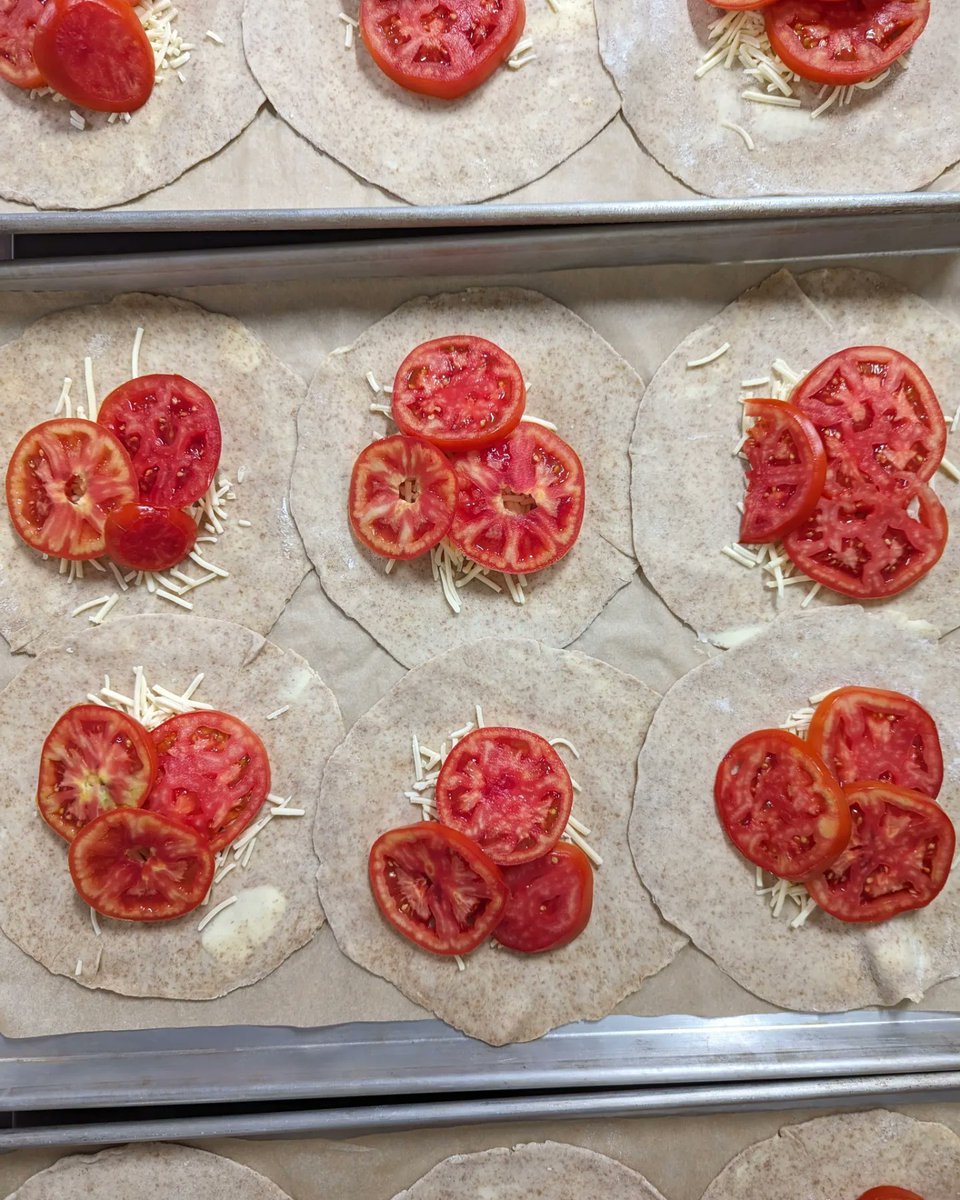 Tomato galettes are around while the tomatoes are good! The steps we take before you get it:

Mix/puck/roll out galette circles
Core/slice/salt/dab tomatoes
Assemble cheese+tomato
Crimp
Bake

Enjoy!