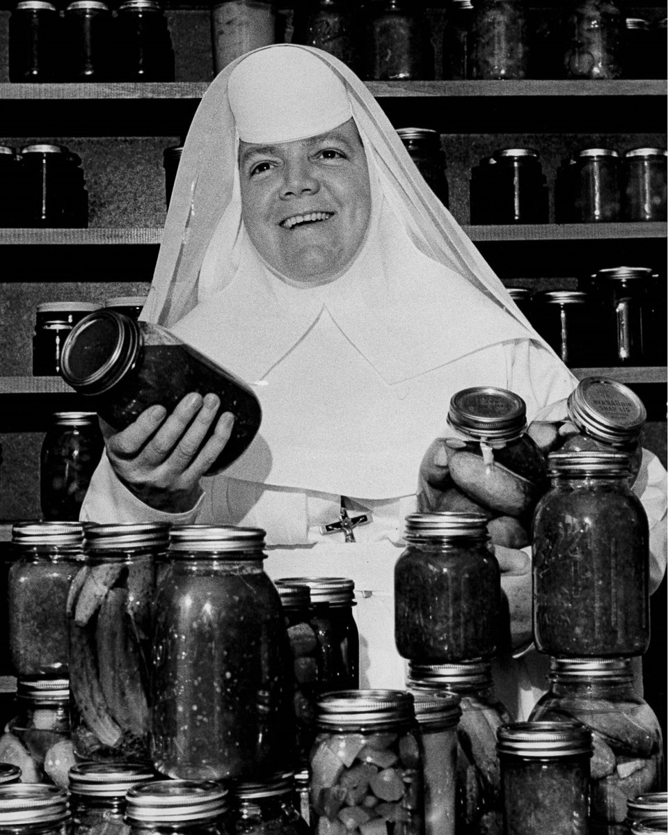 Sister Mary Patricia Doyle, a Religious Sister of the Sisters of Mercy @SistersofMercy, holding jars of pickled cucumbers and other canned foods. 1960s photo from The Mercy Archives at facebook.com/mercyarchiveso….