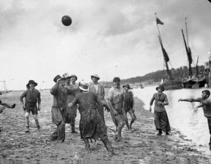 1900 - a group of revellers play football amid the vast mudflats near Southend on Sea (probably Leigh on Sea?) with Thames barges in the background - this seaside resort was always a popular destination for East Enders