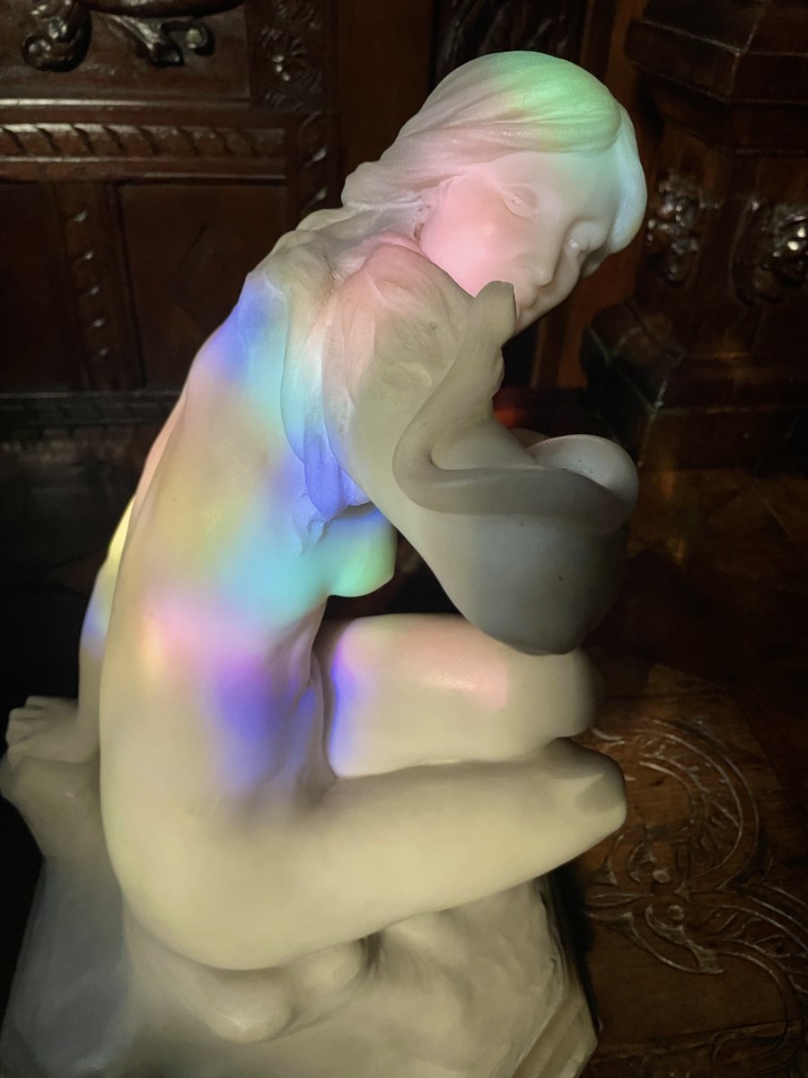 Caught in the Act of Colourful Transformation! Last night, while closing up the house, a magical surprise awaited at the bottom of the stairs. The once white statue, Lilith, was basking in vibrant colours, courtesy of the stained glass windows' giving a playful splash of colour.