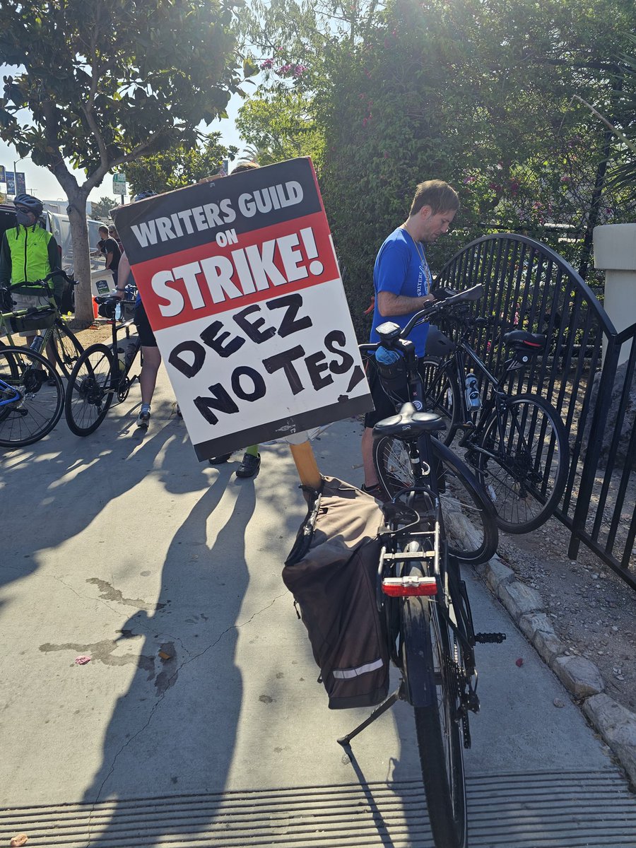 EricaVAINdotCom's tweet photo. Every Thursday we hit the streets on our Bikes!!! Todays start was at #CBSTVCity and the sign of the day on my bike is.... #DEEZNOTES 😝  - @EricaVain #BiketheStrike #WGASTRONG #SAGAFTRAstrike https://t.co/sxKMpZshON