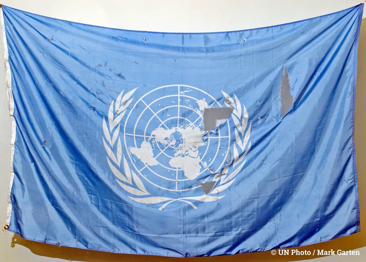 UNGeneva's tweet photo. 20 years ago today, this flag was recovered following the bombing of the @UN headquarters in Baghdad, Iraq.

On #WorldHumanitarianDay, we thank all aid workers across the globe who stay and deliver #NoMatterWhat, and honour those killed and injured in the line of duty. https://t.co/KwTUP1xqiE