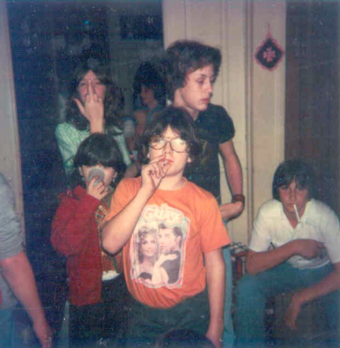 Two kids smoking, one kid flipping the bird, I think another kid may be taking a hit of nitrous oxide. Look, it was the 70s.