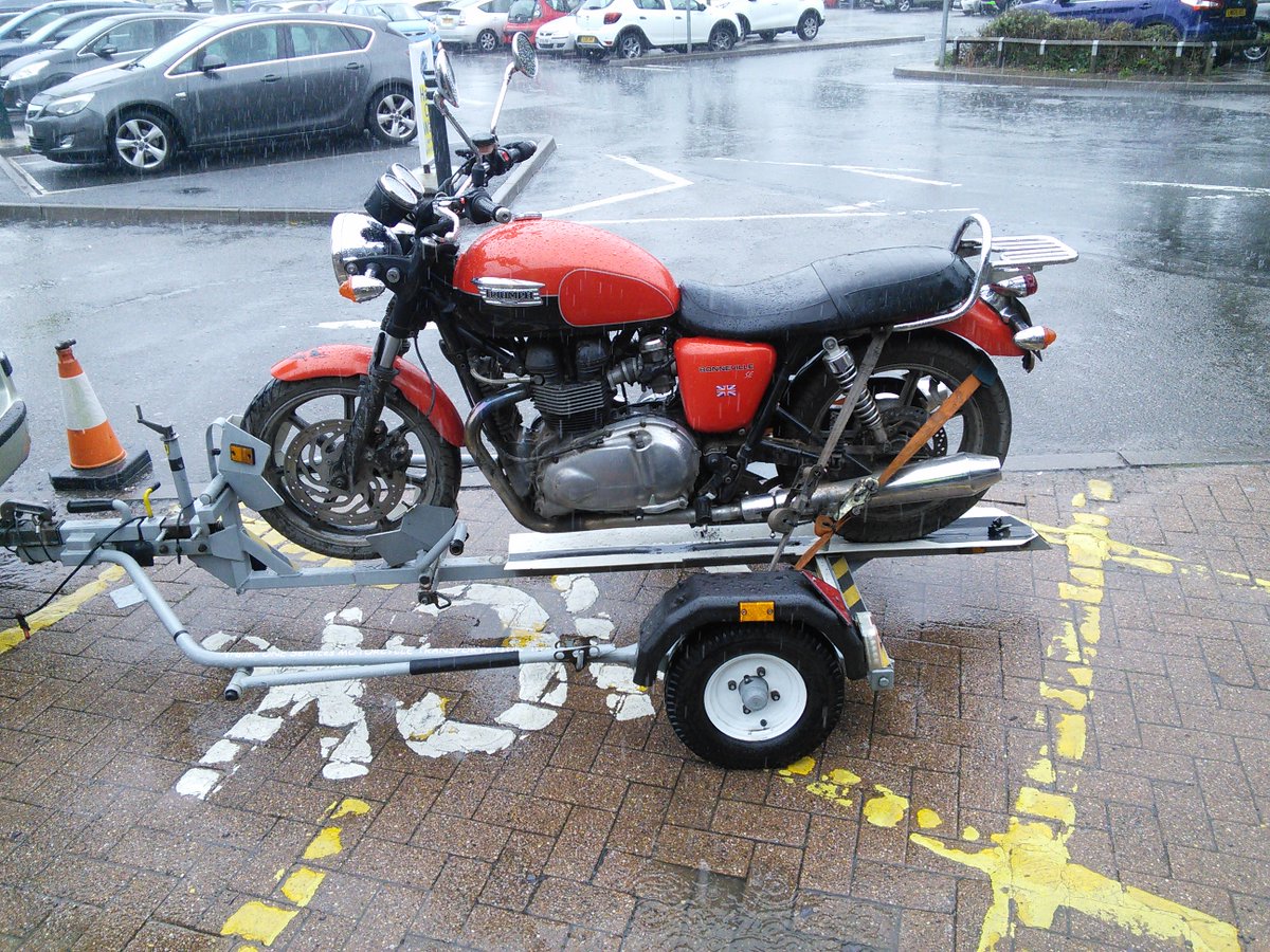 Trailer1one's tweet photo. Triumph Bonneville, very rainy day in Solihull Morrison's foods carpark, on its journey to Sheldon Motorcycles, Birmingham due to side stand switch issues. https://t.co/Rvm1JIxiD6