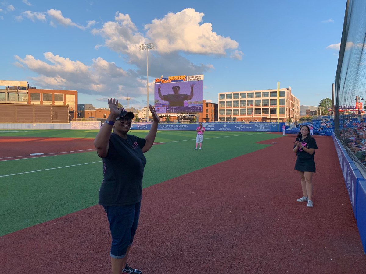 Strength personified: Tonya McQueen took the mound at the @RockersBaseball game after her brave fight with breast cancer. Her family's unwavering support shines through. 'Pink at the Point' auction proceeds go to @AtriumHealth's cancer support programs. 🎗️⚾ #AtriumHealthHeroes