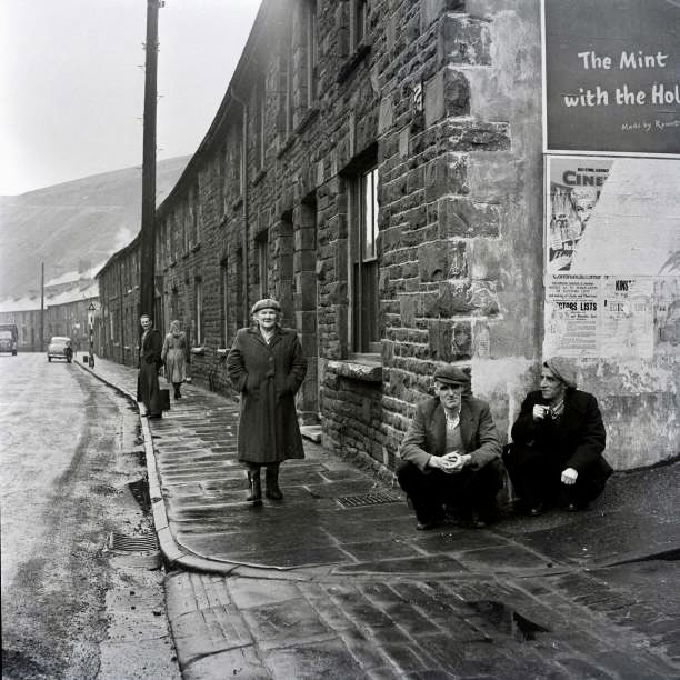 Miners from Aberdare in South Wales holding up the wall of the Boot Hotel March 1954 by Bela Zola