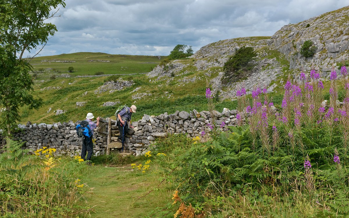 Walkers negotiating a stile on Giggleswick Scar, near Settle, Yorkshire Dales NP