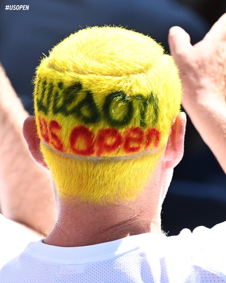 Picture of a man with yellow hair and 'Wilson US Open' painted on his hair. 
