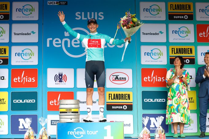 Tarling in a Turquoise leaders jersey holding a bunch of flowers.