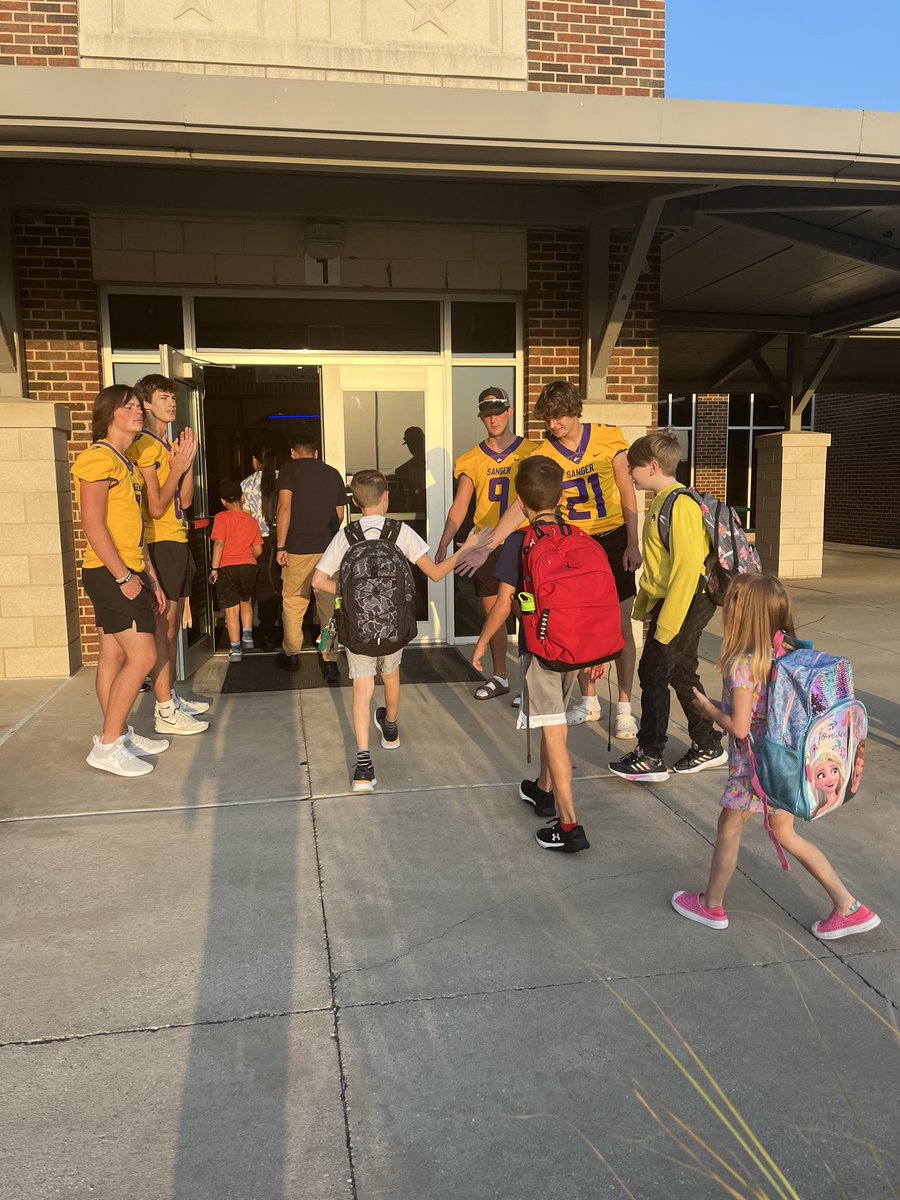 CoachChadRogers's tweet photo. High five Friday.  Welcoming the little ones to school.  Smiles all the way around.  Not sure the ones in jerseys realize how important they are.  They do now.  #begreat https://t.co/1qOmTTyEcO