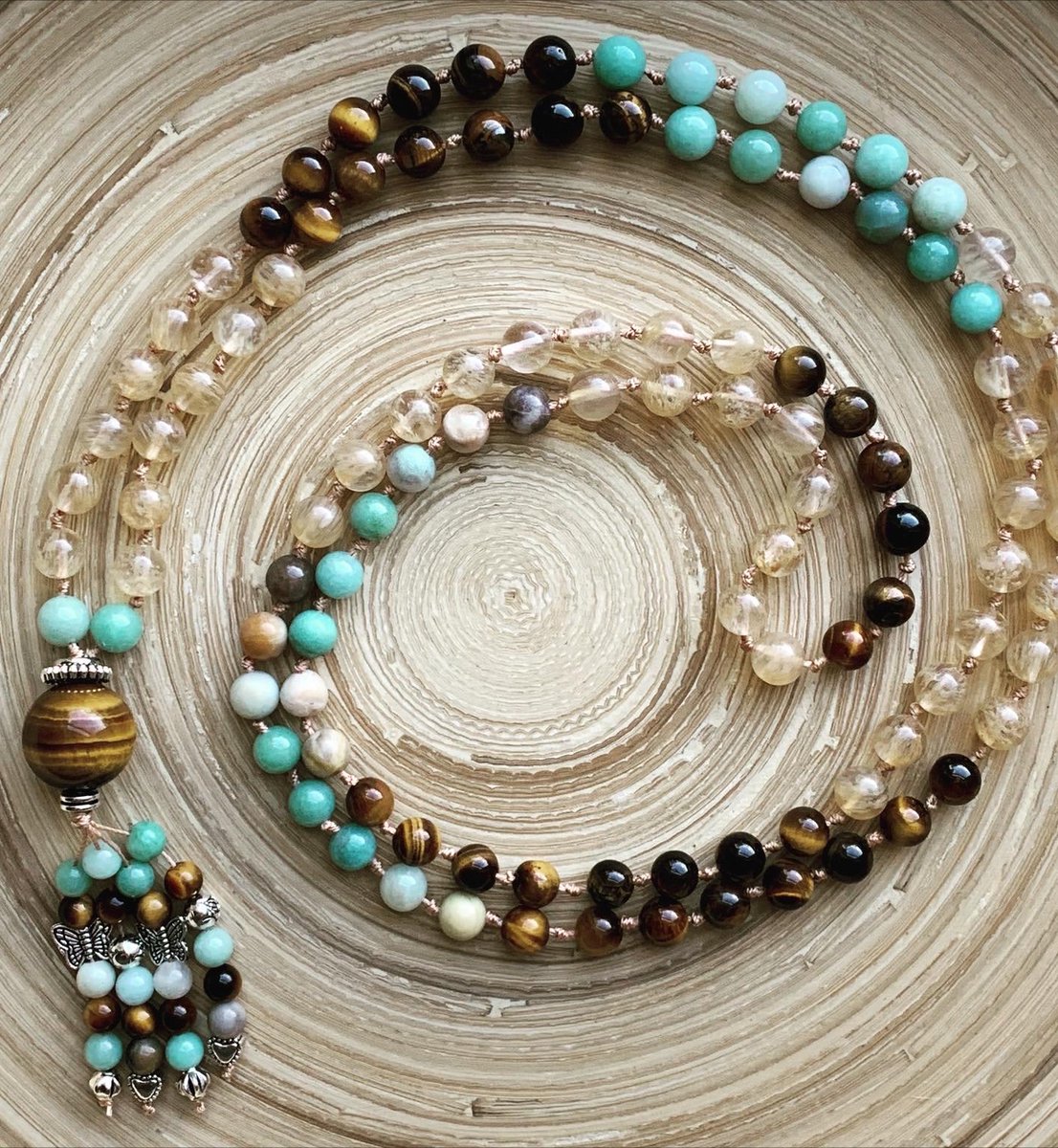 This pretty tiger’s eye, amazonite, and golden healer quartz 108 bead mala, hand-knotted between each  bead by me is waiting in my shop. She’s a total flirt, with tiger’s eye flash for days. Link in bio. 🤎💛🩵