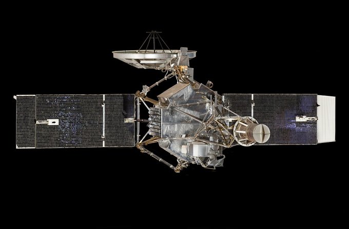 Spacecraft with solar panels extending from it photographed against a black background. 