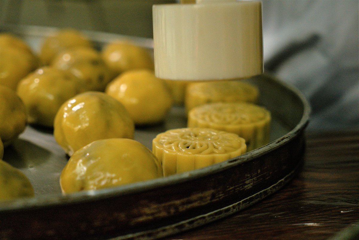 ChinaDaily's tweet image. Mixing flour with walnuts, raisins, peanuts, and more, then into the oven it goes! Experience the magic of "firewood mooncakes", where wood fire roasts the top and charcoal works below. #food #mooncake