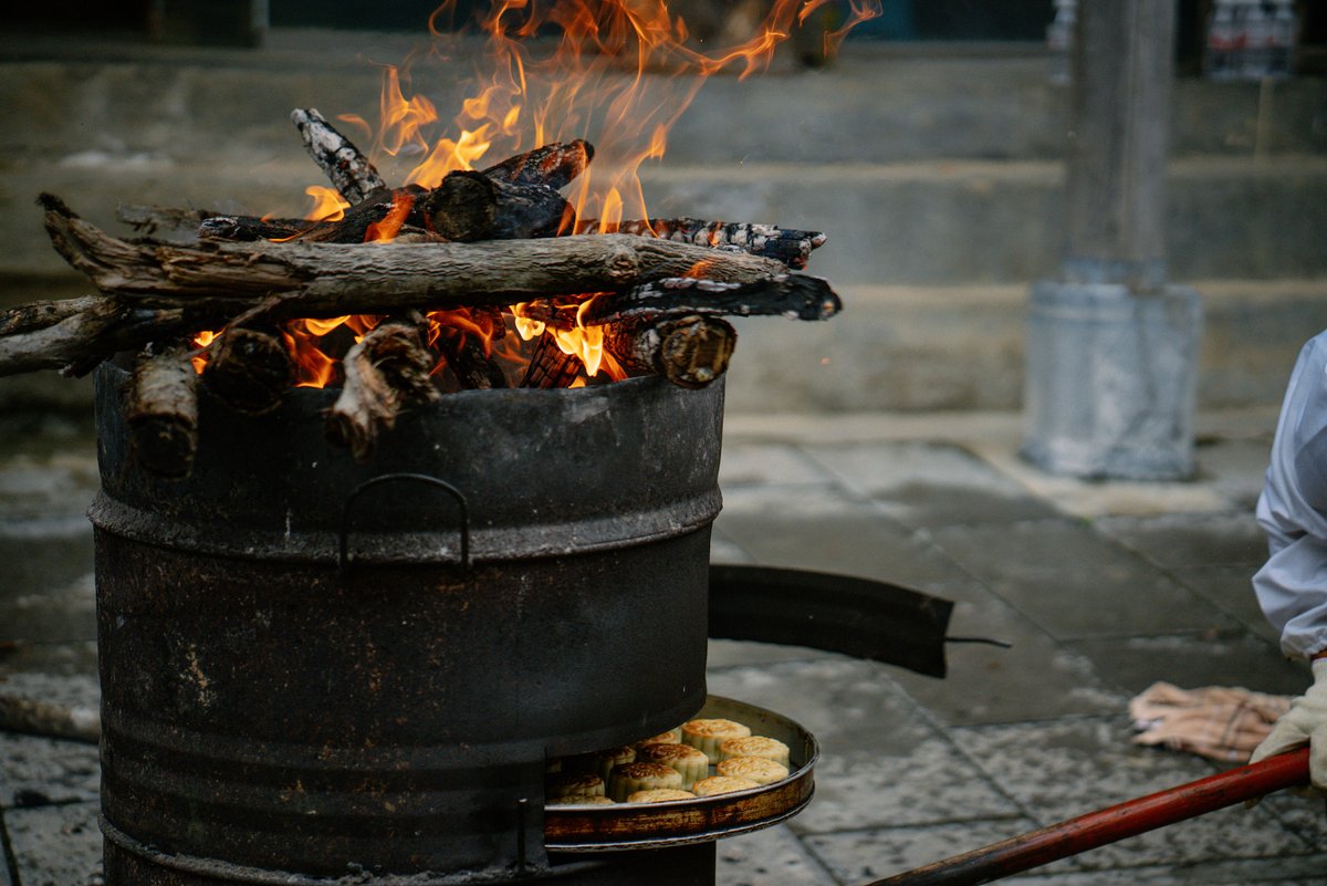 ChinaDaily's tweet image. Mixing flour with walnuts, raisins, peanuts, and more, then into the oven it goes! Experience the magic of "firewood mooncakes", where wood fire roasts the top and charcoal works below. #food #mooncake