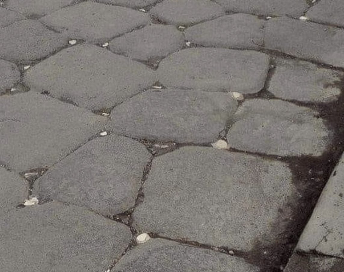 An ancient Roman road in Pompeii. These roads were adorned with dotted white stones, which reflected the moonlight, acting as street lights to help people walk on the street after dark.
