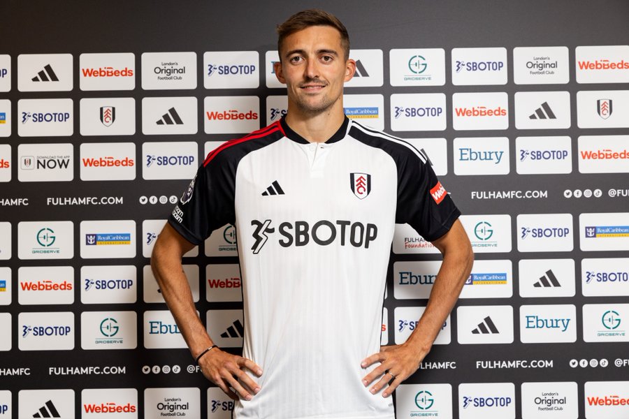 Timothy Castagne stands in front of the sponsor board at Craven Cottage.