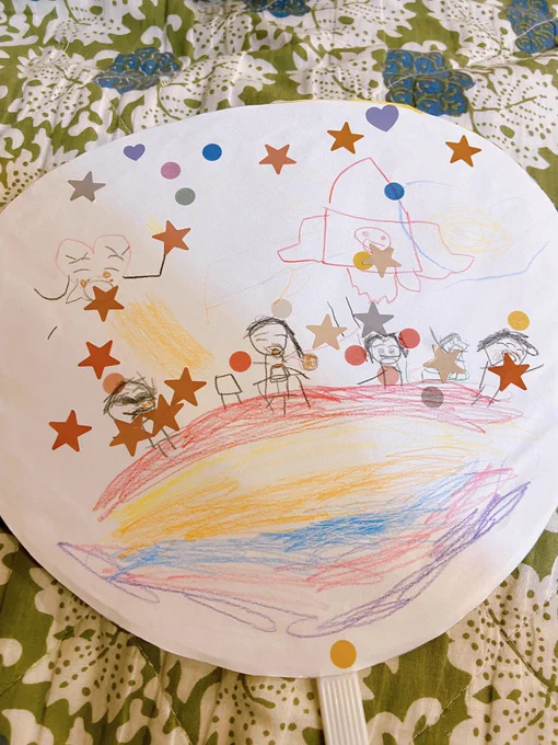 娘が作ってきたうちわの絵が可愛い。星のクッキーを虹の上でみんなで食べてるらしくて夢があるなぁ、、