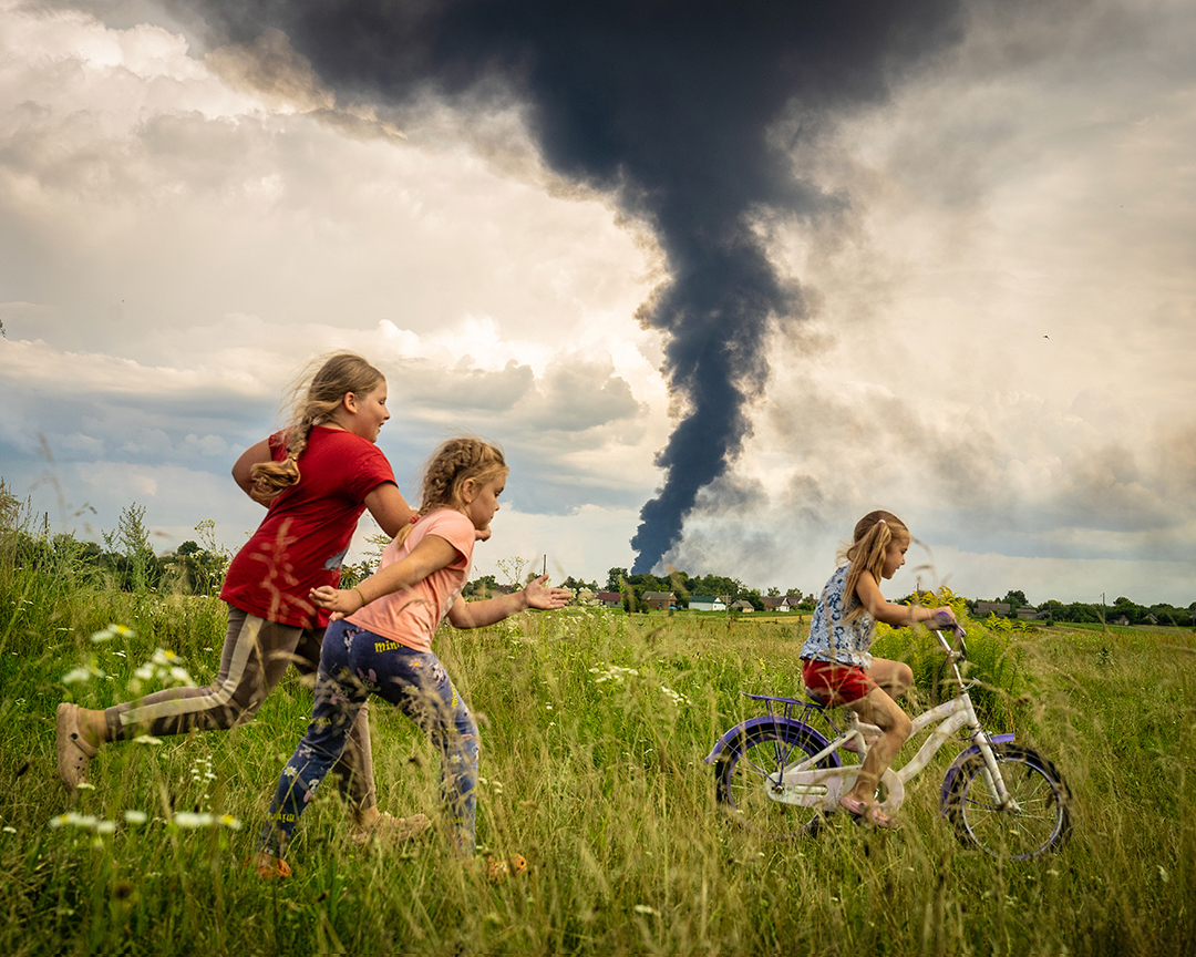 Kids learning how to ride a bicycle in the fields of Ukraine.

In the background aftermath of an overnight Russian drone attack on the Rivne region and a burning oil depot.

#україна #ukraine #ukraine2023 #humanrights #warphotography #warinukraine #ukrainewar #вiйна