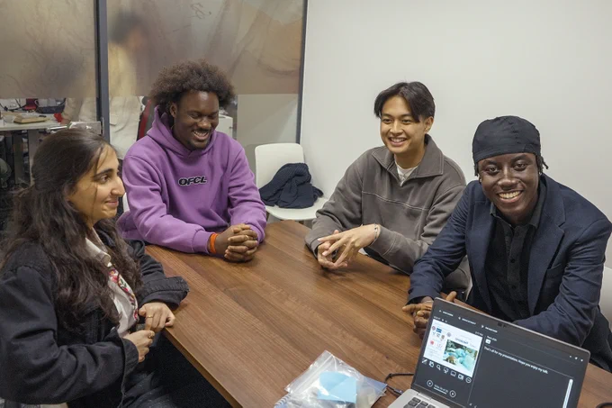 Four students sitting around a table smiling