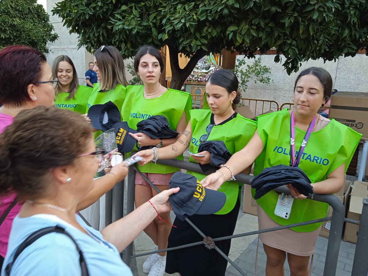 UCAM's tweet photo. 📸 Voluntarios UCAM participaron ayer en la Romería de Murcia entregando gorras a los romeros que acompañaron a la Virgen de la Fuensanta en su regreso a su santuario en el monte. https://t.co/wNSV7oF4nz