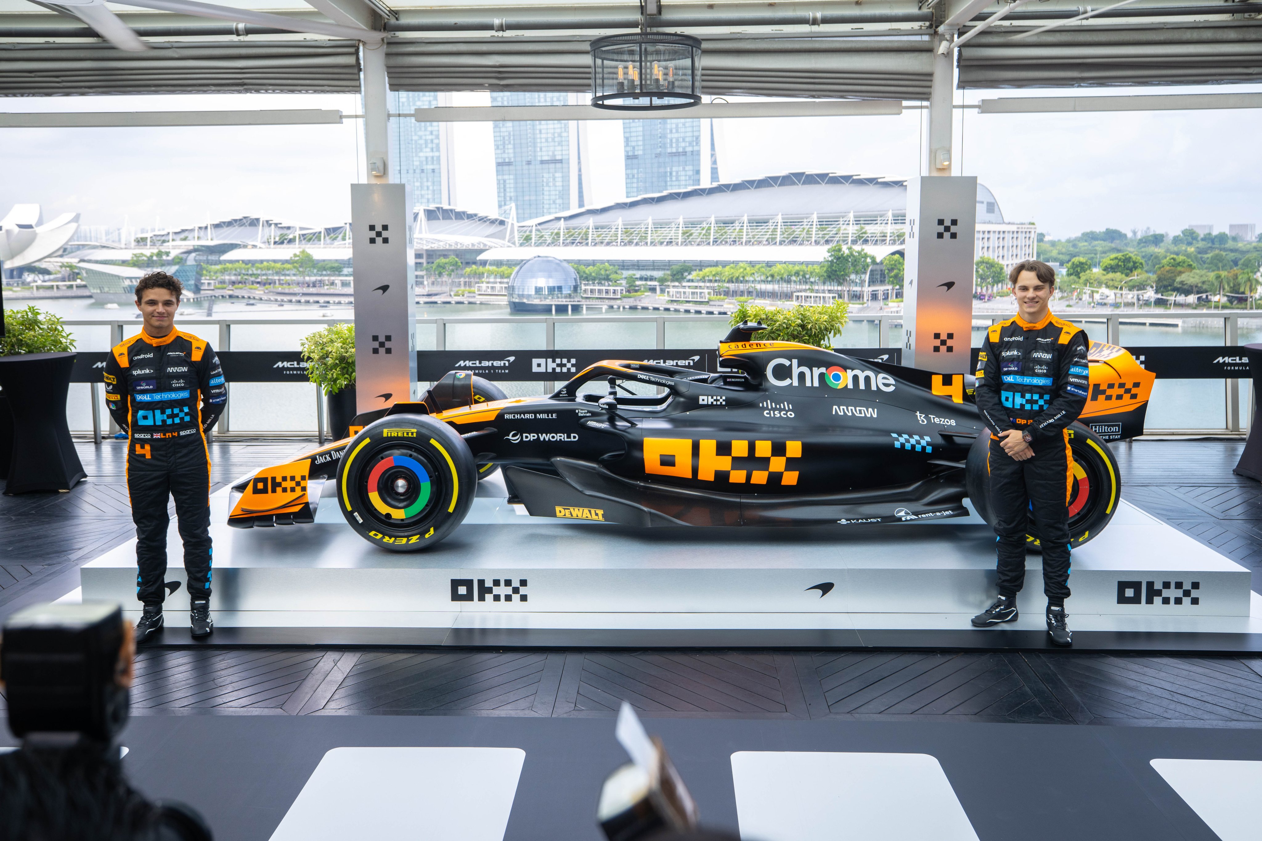 McLaren drivers Lando Norris and Oscar Piastri stand beside the 'stealth' liveried car.