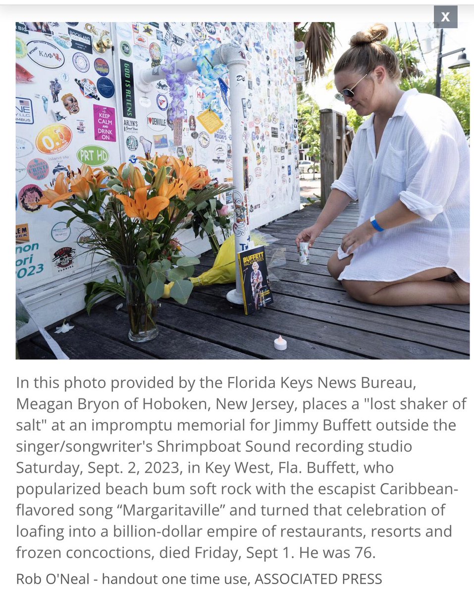 In this photo provided by the Florida Keys News Bureau, Meagan Bryon of Hoboken, New Jersey, places a 'lost shaker of salt' at an impromptu memorial for Jimmy Buffett outside the singer/songwriter's Shrimpboat Sound recording studio Saturday, Sept. 2, 2023, in Key West, Fla.