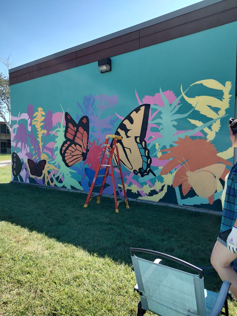 ArtsPentucket's tweet photo. The Merrimac Mural is looking better and better everyday! Since the teal background was painted, Jenn Houle has brought this piece of art to life with colorful and vibrant plants and butterflies! Thank you, Jenn, we can’t wait to see what the finished product will look like! https://t.co/KUhmHbdEvi
