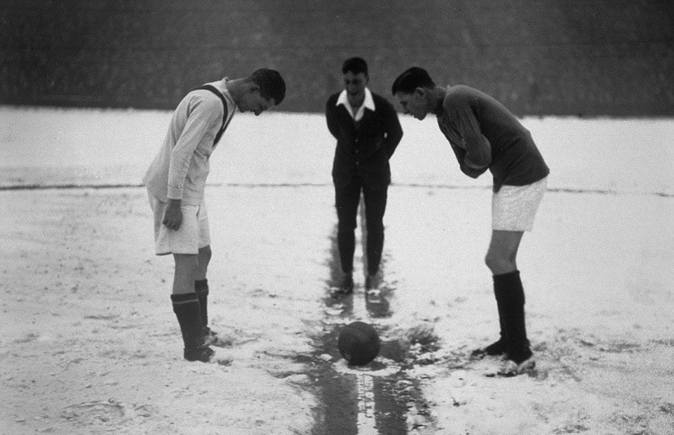 The referee tosses up a coin on a snow-covered football pitch at the start of the match between Arsenal and Manchester United at Highbury, 1926. 

Photo: Getty Images