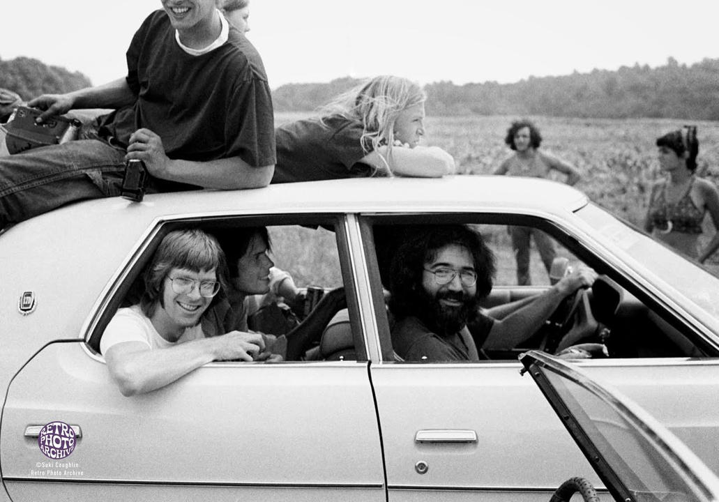 THE STORY BEHIND THE PHOTO ...
We've all seen this awesome photo of The Grateful Dead on the way to the 1973 Summer Jam at Watkins Glen. There they are, sitting in traffic, relaxed and smiling, with fans draped around their car. It really tells the story of the event and the era