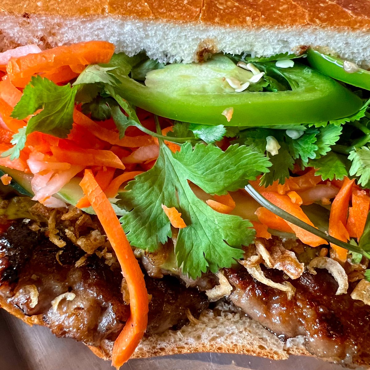 Giving you that close up angle of our Medallion Bánh Mì 😮 Pork lemongrass patties, crispy fried onions, green onion scallion oil, cucumbers, sweet pickled carrots and daikons, cilantro, Mommy's Signature Sauce, chicken pate, jalapeños 😋 Open today til Sat at 10:30 AM to 2 PM!