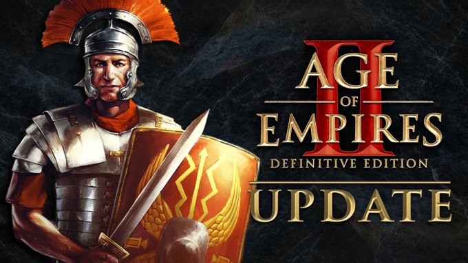 An Age of Empires II: Definitive Edition update announcement. A crop of the central figure from the Age of Empires II: Definitive Edition — Return of Rome retail key art, Trajan, a man wearing metal armor, a brick red short-sleeved tunic, and a plumed Roman helmet is positioned against a black marble background. He carries a short sword and a legionnaire scutum. 