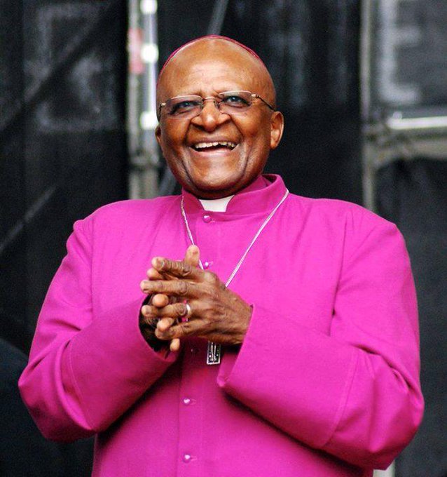 Archbishop Desmond Tutu smiling with his hands clasped.