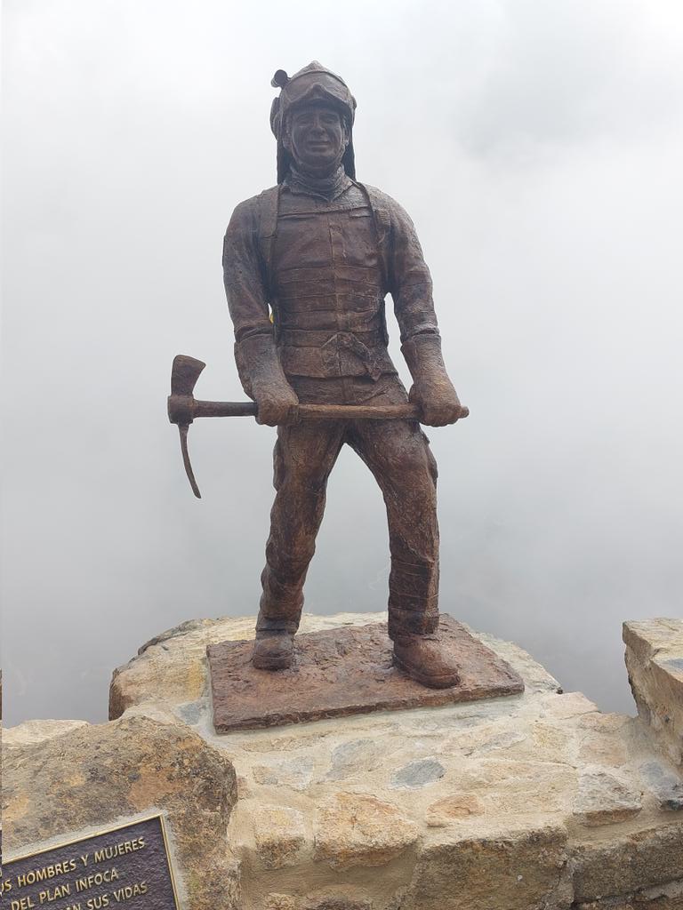 Plan_INFOCA's tweet photo. La estatua de Carlos es obra de Amando López Gullón, es realista y refleja sus rasgos físicos, con una altura de 1,80 m de bronce, se corresponde con la imagen de un bombero forestal provisto de #EPI, mochila y pulaski. El pedestal es de piedra de la zona y tiene con dos leyendas https://t.co/f4reqP7iW7