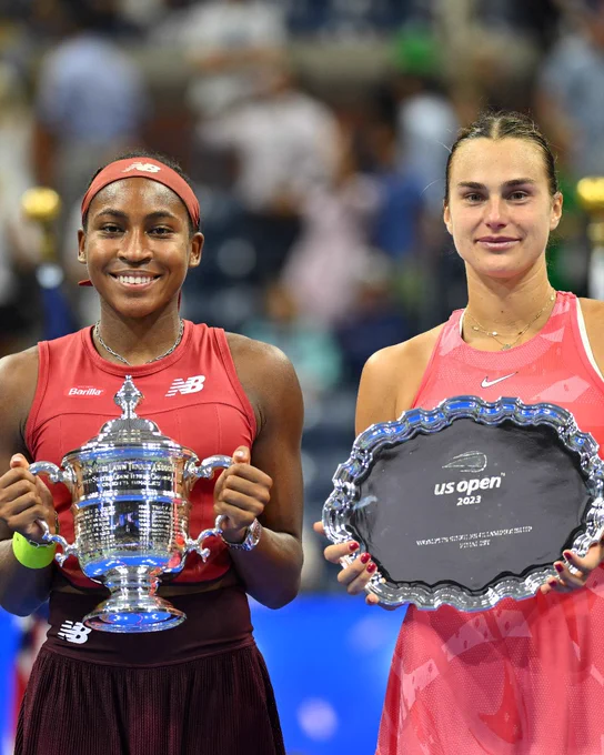 Coco Gauff and Aryna Sabalenka standing with their US Open trophies. 