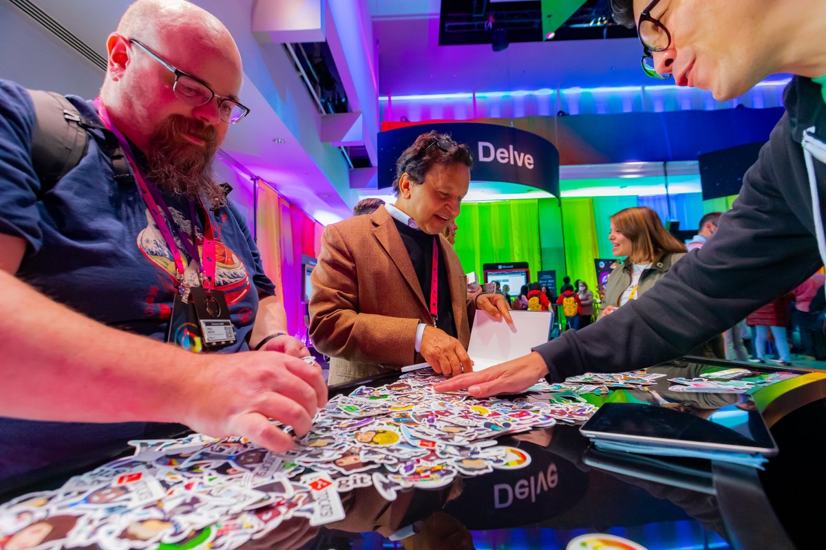 2 people searching through a lot of Octocat stickers with help from a GitHub employee