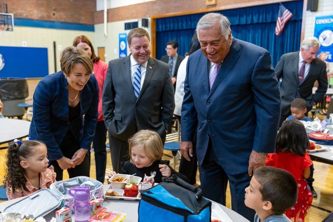 Governor Healey and Speaker Mariano speaking with students at lunch table.